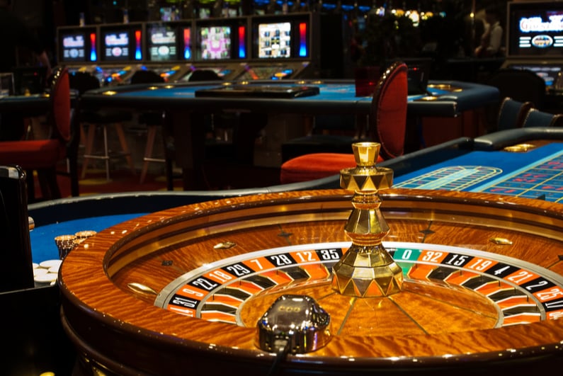 Golden Casino theme. High contrast image of casino roulette, poker game, dice game, poker chips on a gaming table.