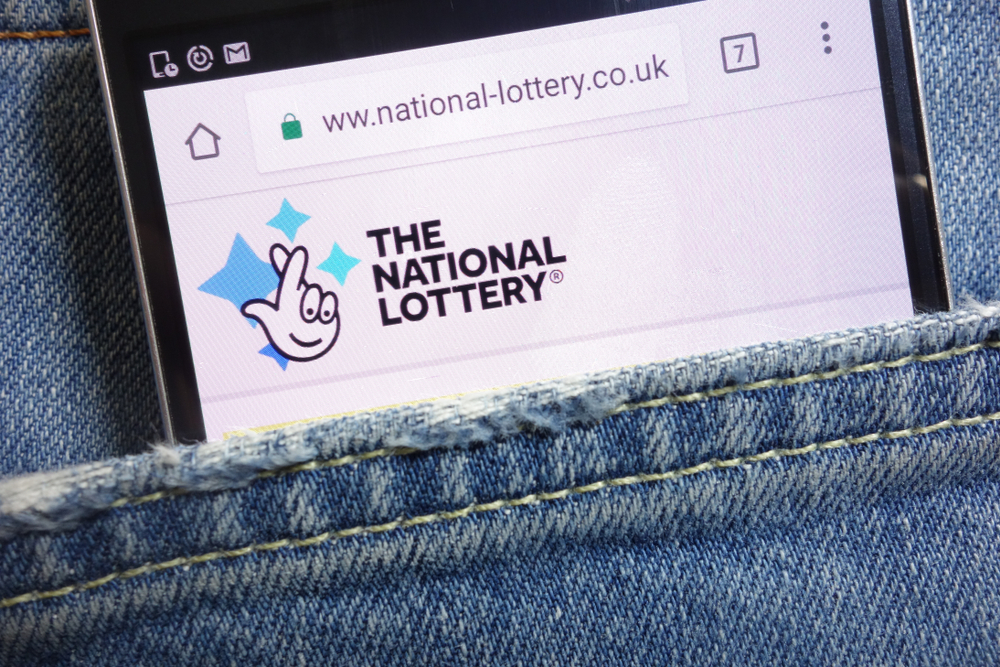 mobile phone inside denim pocket displaying the uk national lottery website