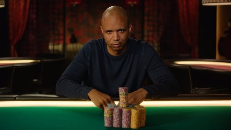 Phil Ivey sitting at poker table with stacks of chips.