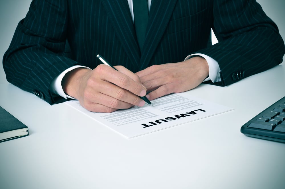 man in suit signing lawsuit paper