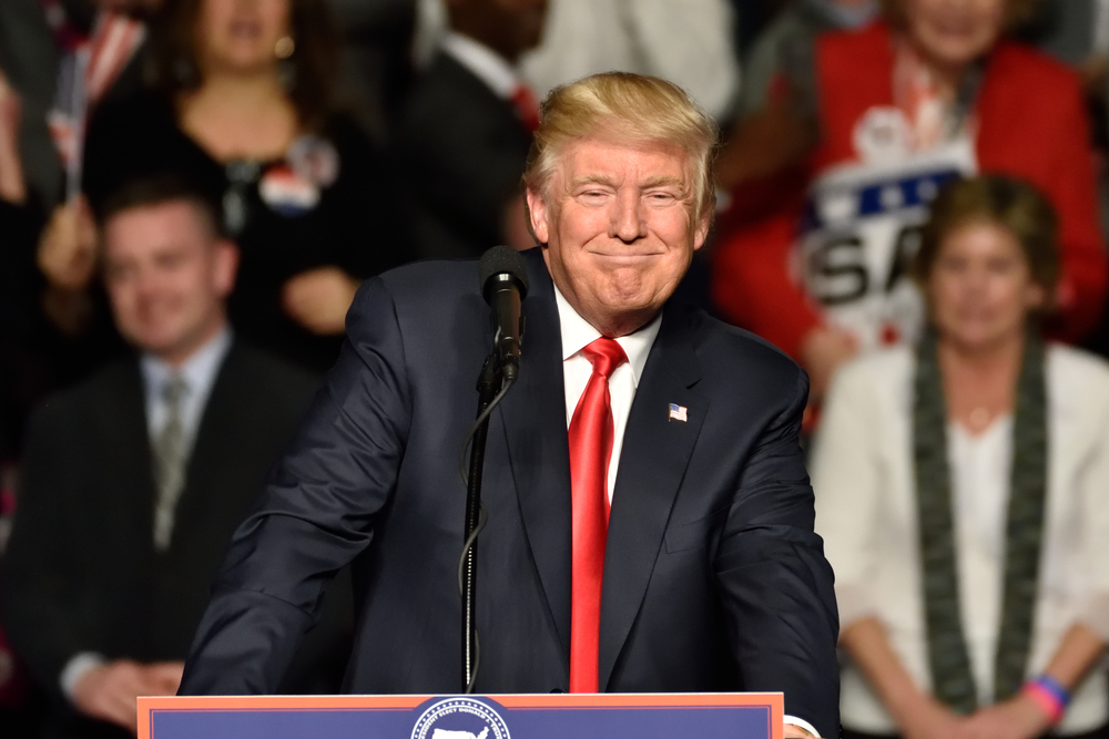 US President Donald Trump at podium surrounded by supporters