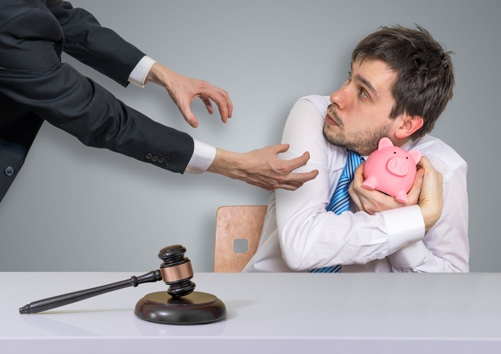 Man keeping piggy bank from businessman with gavel