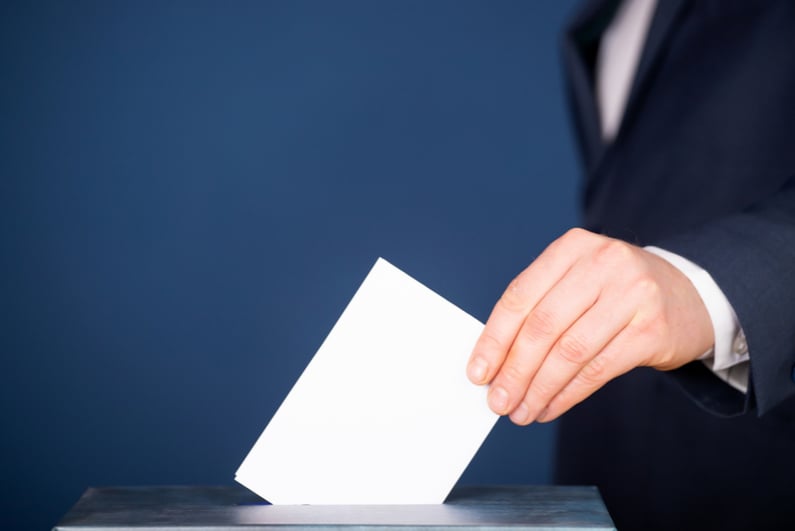 Man dropping ballot into a box